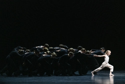 en jente fra ballettskolen i front av en stor gjeng med sortkledde dansere