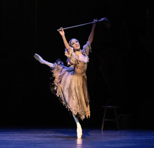Ballerina på tåspiss som løfter en kost