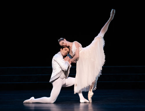 Ballerina på tåspiss lener seg mot knelende lykkelig mannlig danser