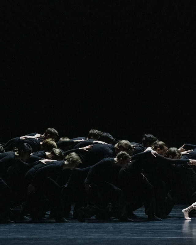 en jente fra ballettskolen i front av en stor gjeng med sortkledde dansere