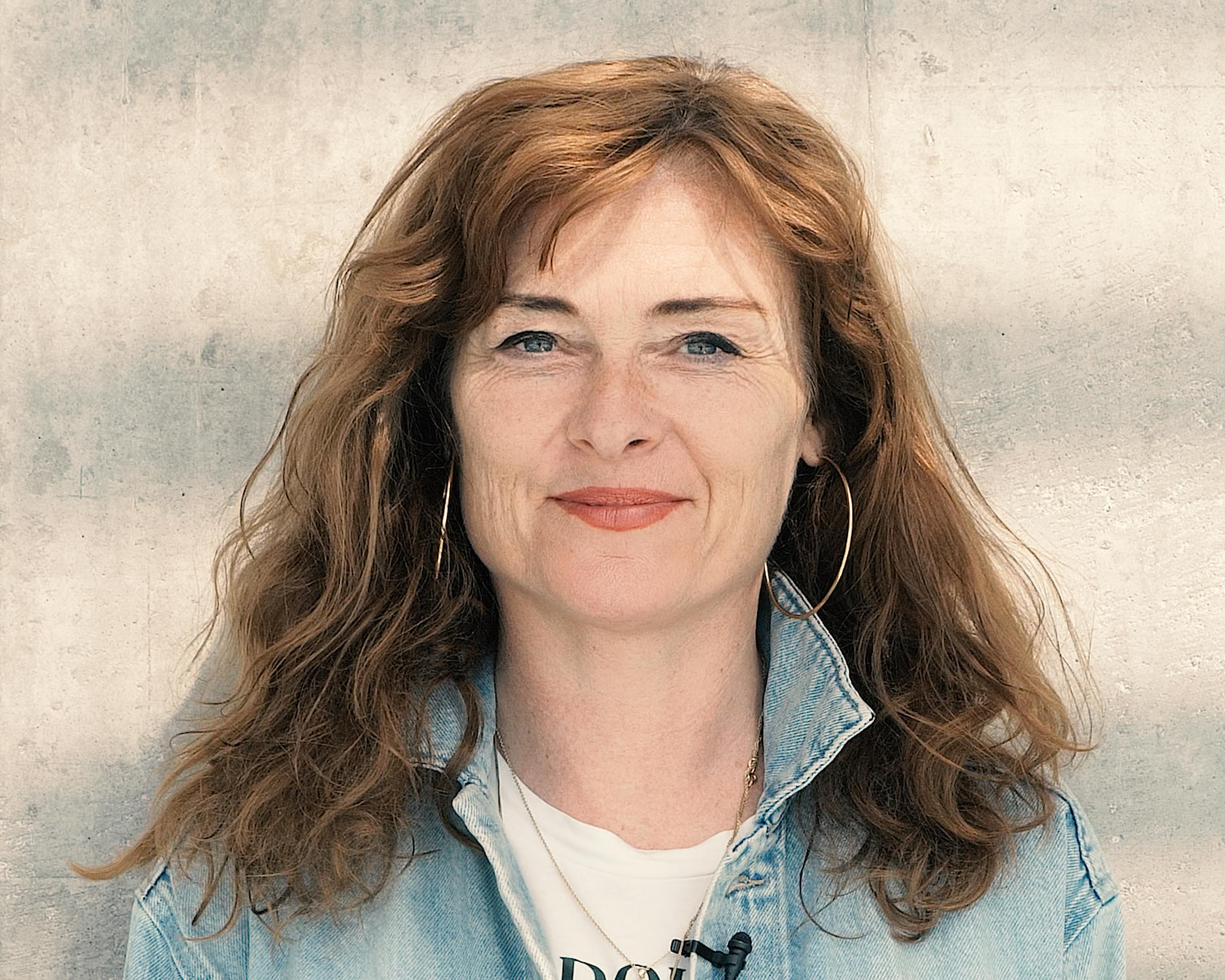 Katrine Wiedemann smiler mot en grå vegg