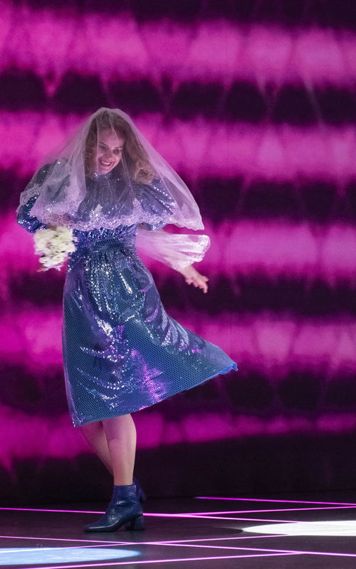 Dansende kvinne i lilla kjole og med brudeslør på hode