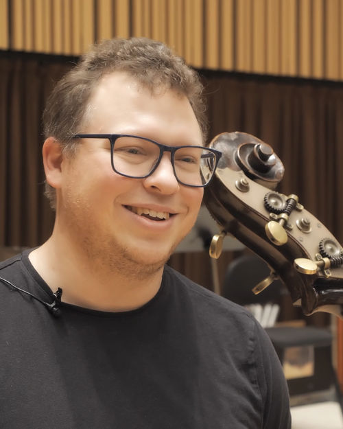 Mann med briller ved siden av halsen på en kontrabass