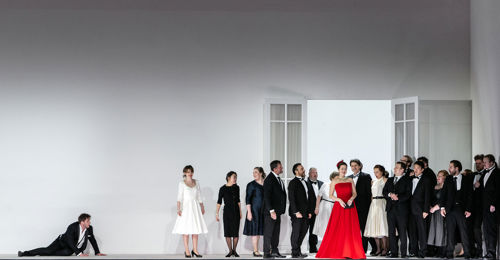 En mann ligger på bakken, kvinne i rød kjole står sammen med andre festkledde