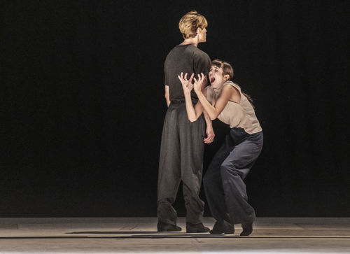 en mannlig danser står med ryggen til mens den kvinnlige danseren bøyer seg som om hun er i smerter