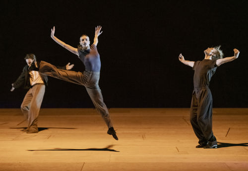 danser hopper mens to menn i bakgrunnen strekker på armene