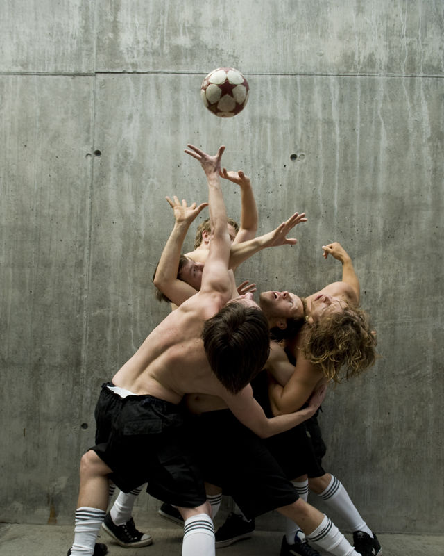 Fire menn danser og kjemper om en fotball