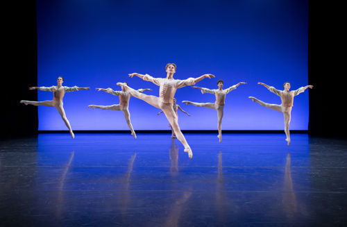 mannlige dansere kledd i hvitt mot blå bakgrunn