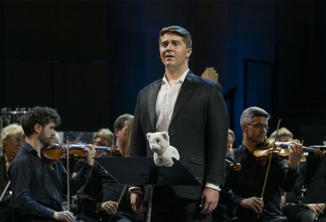 Mann med bamse foran orkester
