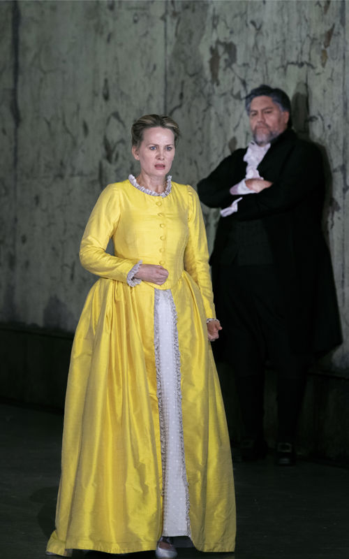 kvinne i gul lang kjole og mann som lener seg mot vegg