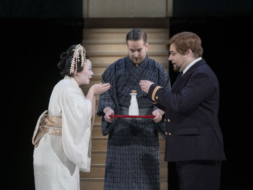 Kvinne i japansk brudedrakt skåler med mann i uniform, mann i kimono med flaske på serveringsbrett