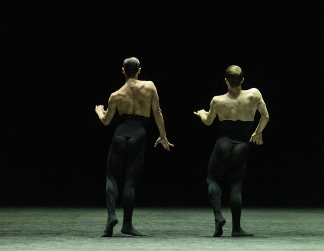 to menn danser med ryggen mot publikum
