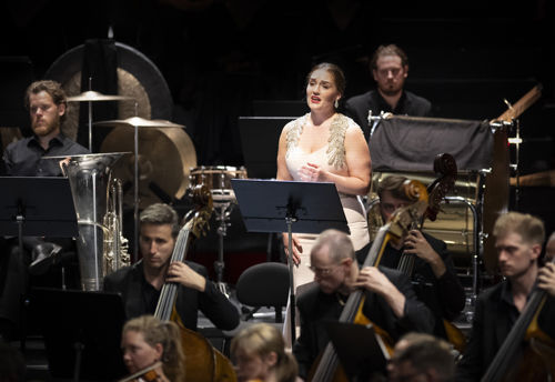 kvinne i lys kjole blant orkestermusikere