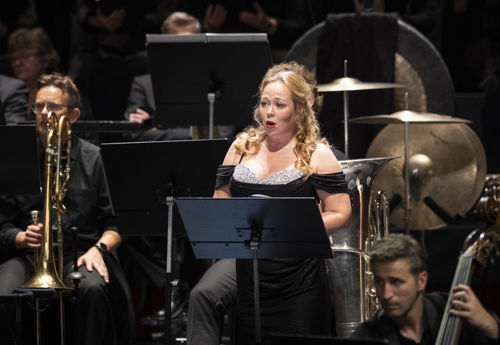 Kvinne i konsertkjole blant orkestermusikere