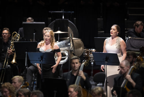 To sangere i konsertkjoler blant orkestermusikere