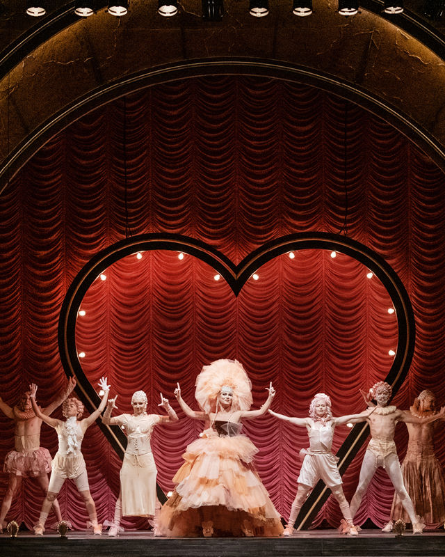 Dansere med kostymer foran hjerte på en scene