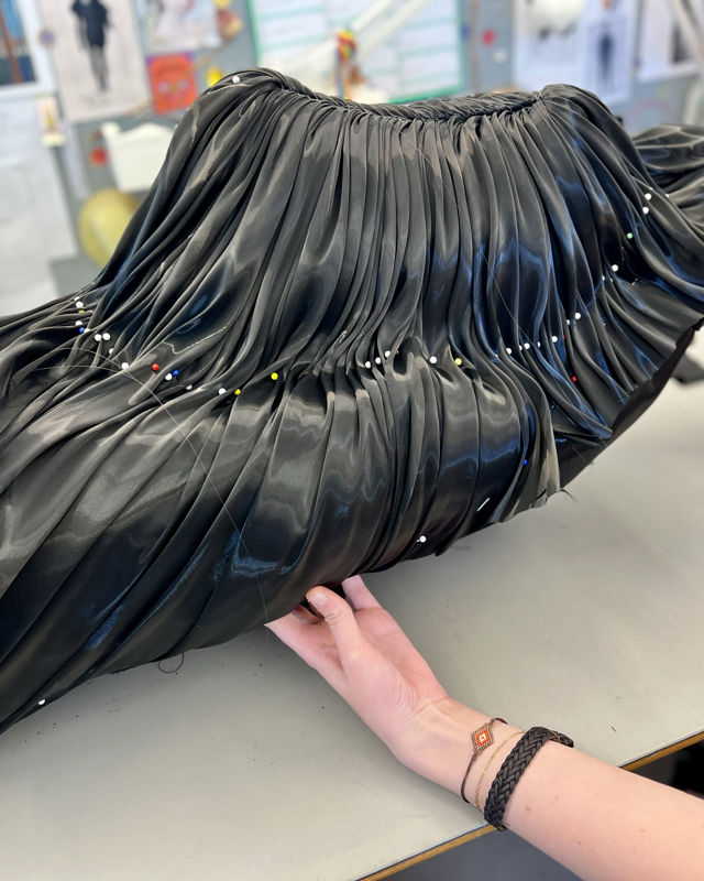 To hender holder et svart kostyme i vevd plast