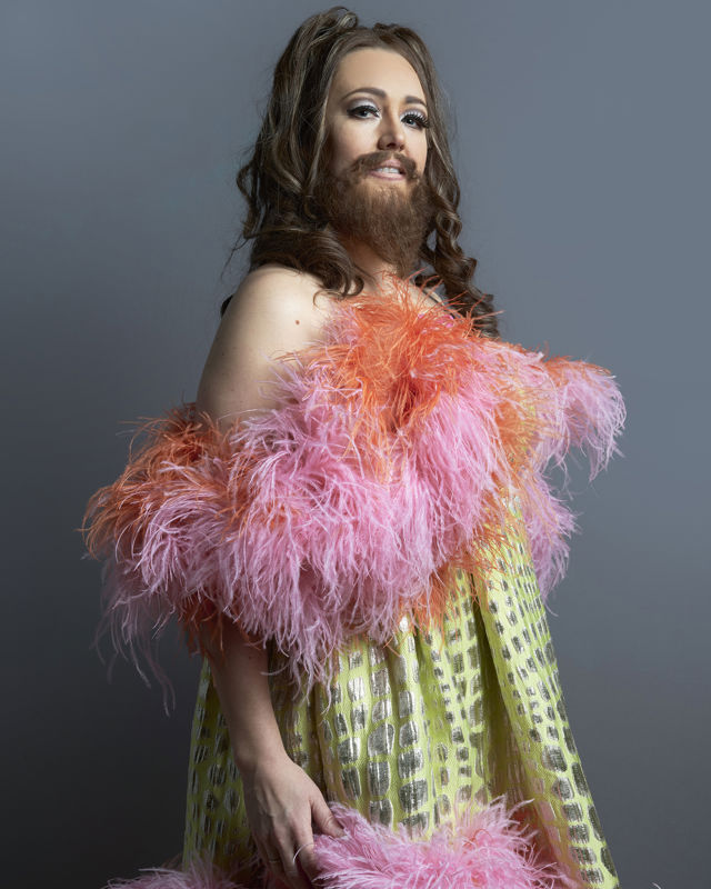 Dame med strutsekjole i mange farger, langt hår og skjegg