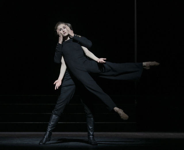 Danser løftes i en dynamisk bevegelse på mørklagt scene