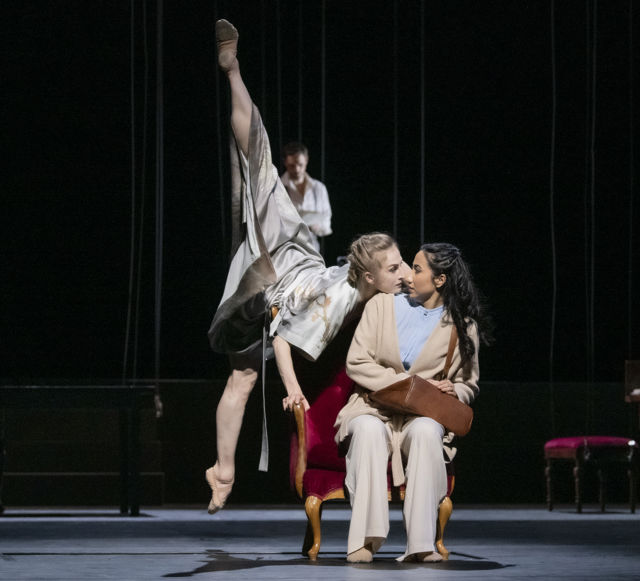 en kvinne hopper mot en annen som sitter i en stol og holder på vesken sin