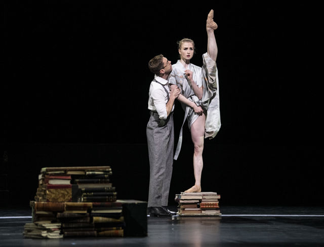 en kvinne på en stabel av bøker, holdes tett av en mann