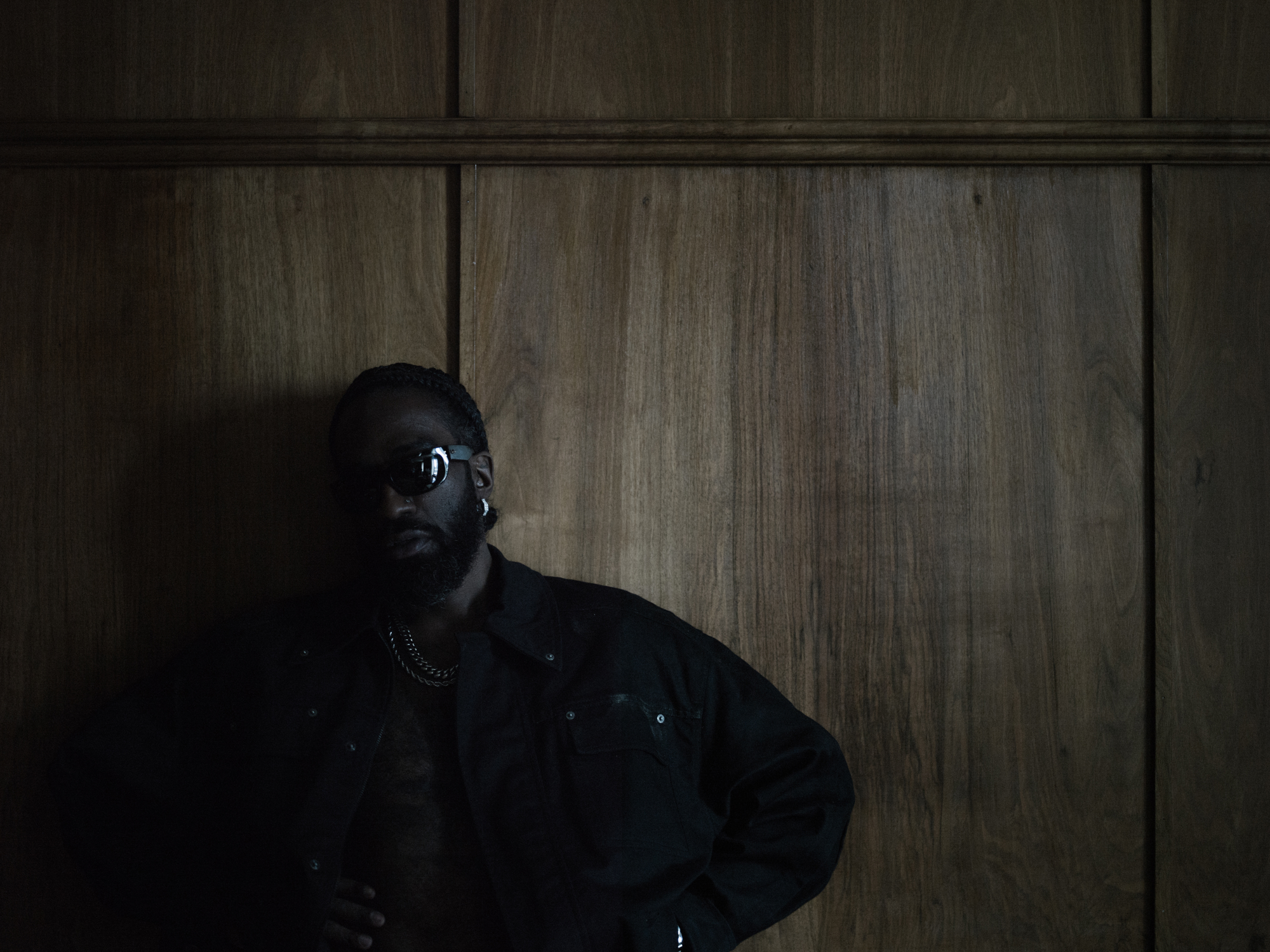 Bilde av mørk mann med solbriller delvis i skygge