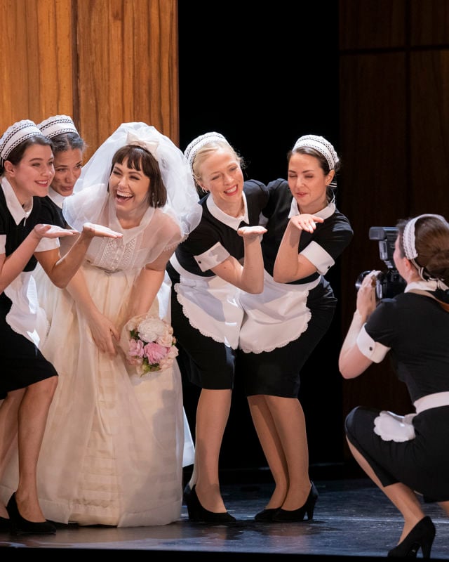 Dame i brudekjole med tjenestejenter ved siden av