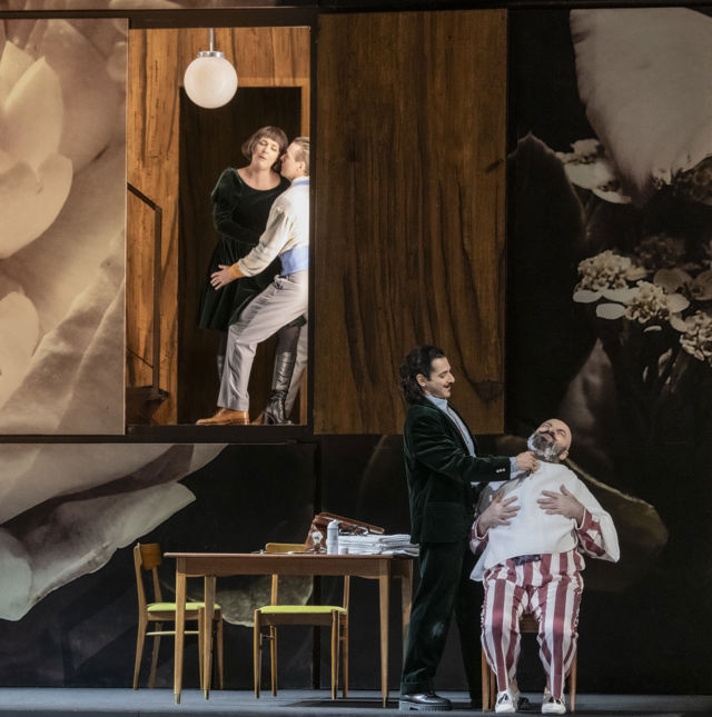 Kvinne og mann i tett omfavnelse oppe på et platå, mann barberer en annen mann i pysjamas