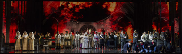 Mange mennesker i kostymer på scene mot rød bakvagg