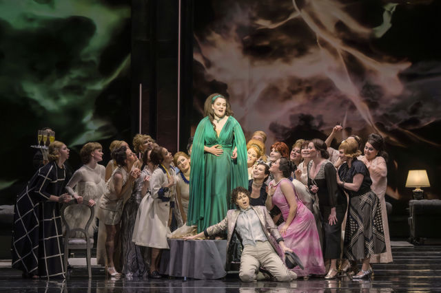 Scenebilde av kvinne i grønn kjole på lite podie blant mange mennesker