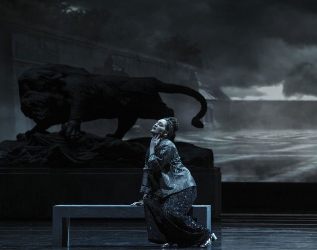 Scenebilde av kvinne på benk, mot mørk og mystisk bakgrunn