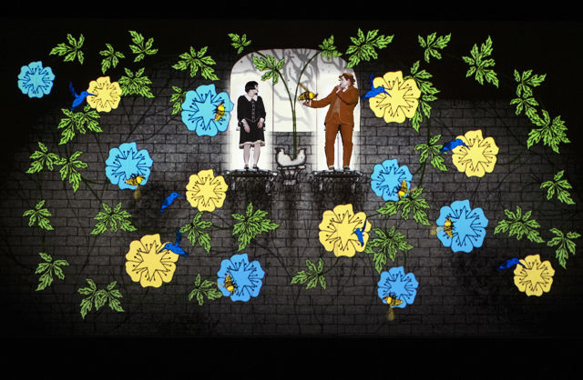 En mann og en kvinne står oppe på to platåer på en vegg, med animerte blomster rundt.