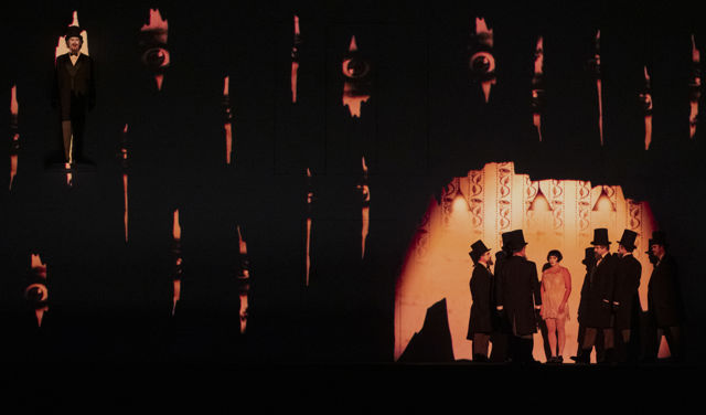 Scenebilde med menn med flosshatt i ring rundt kvinne i kort kjole