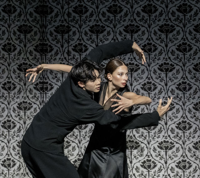 danser holder rundt annen danser, foran mønstret vegg