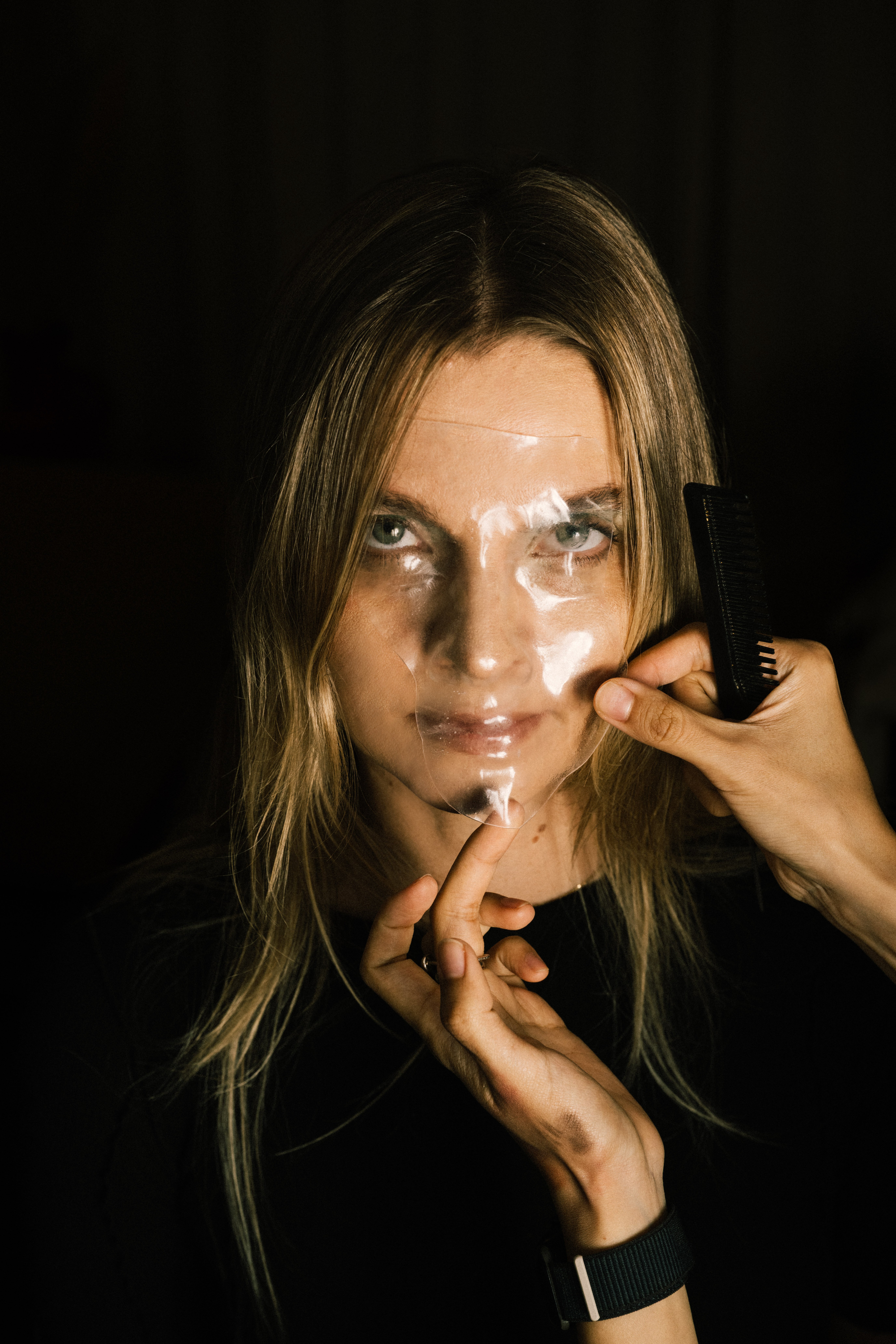 Portrett av kvinne, der noen holder en gjennomsiktig plastmaske mot ansiktet hennes