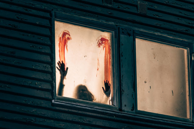Omriss av blodige hender og blod på innsiden av et opplyst vindu