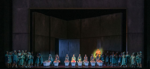 Ensemble på scenen i badekar foran et mørkt scenebilde.